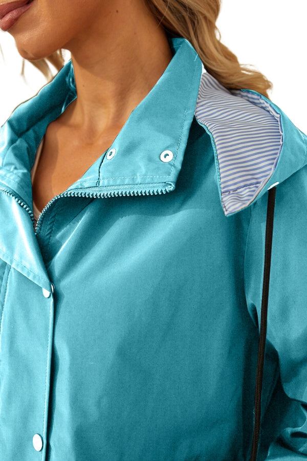 Close-up of woman wearing turquoise water resistant windbreaker with hood and striped lining