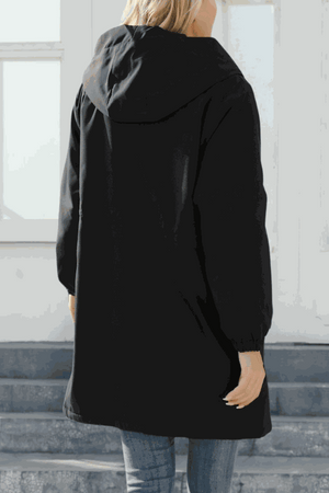 Black water-resistant windbreaker jacket with hood and elastic waist, shown from back on woman indoors