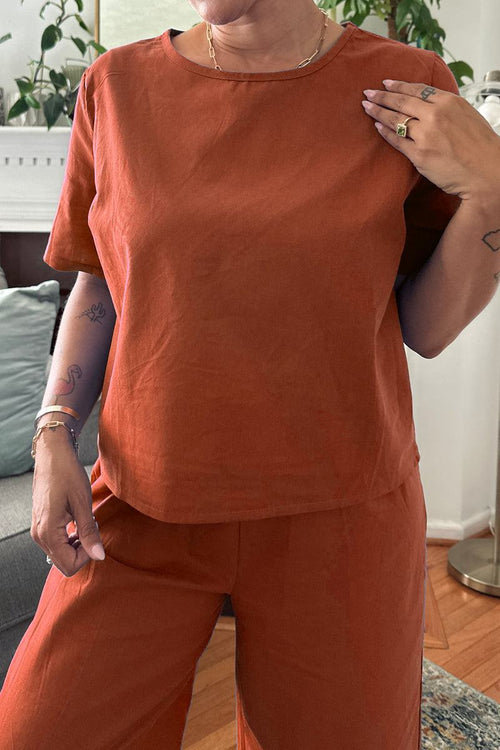 Woman wearing rust-colored loose fit co-ord set with short sleeves and wide-leg pants indoors