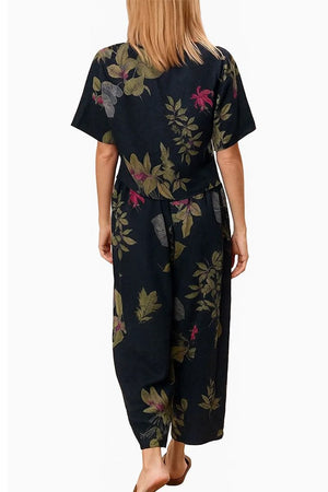 Back view of a woman wearing a black floral loose fit co-ord set with wide-leg trousers and relaxed short-sleeve top