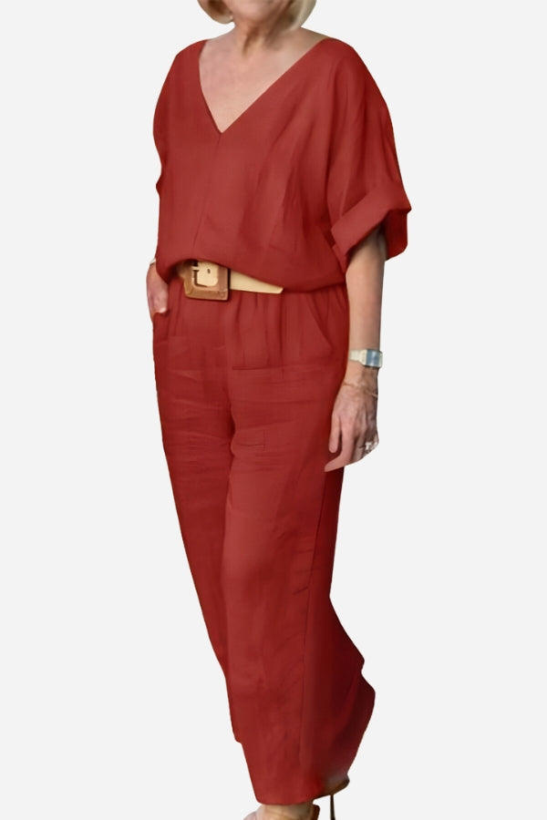 Woman wearing a red V-neck cotton two-piece trouser set with rolled mid-length sleeves and straight-leg pants.