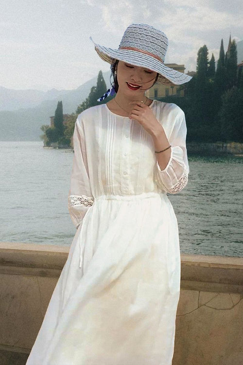 Woman wearing 100% linen coastal shift dress with long sleeves and lace detail by the water