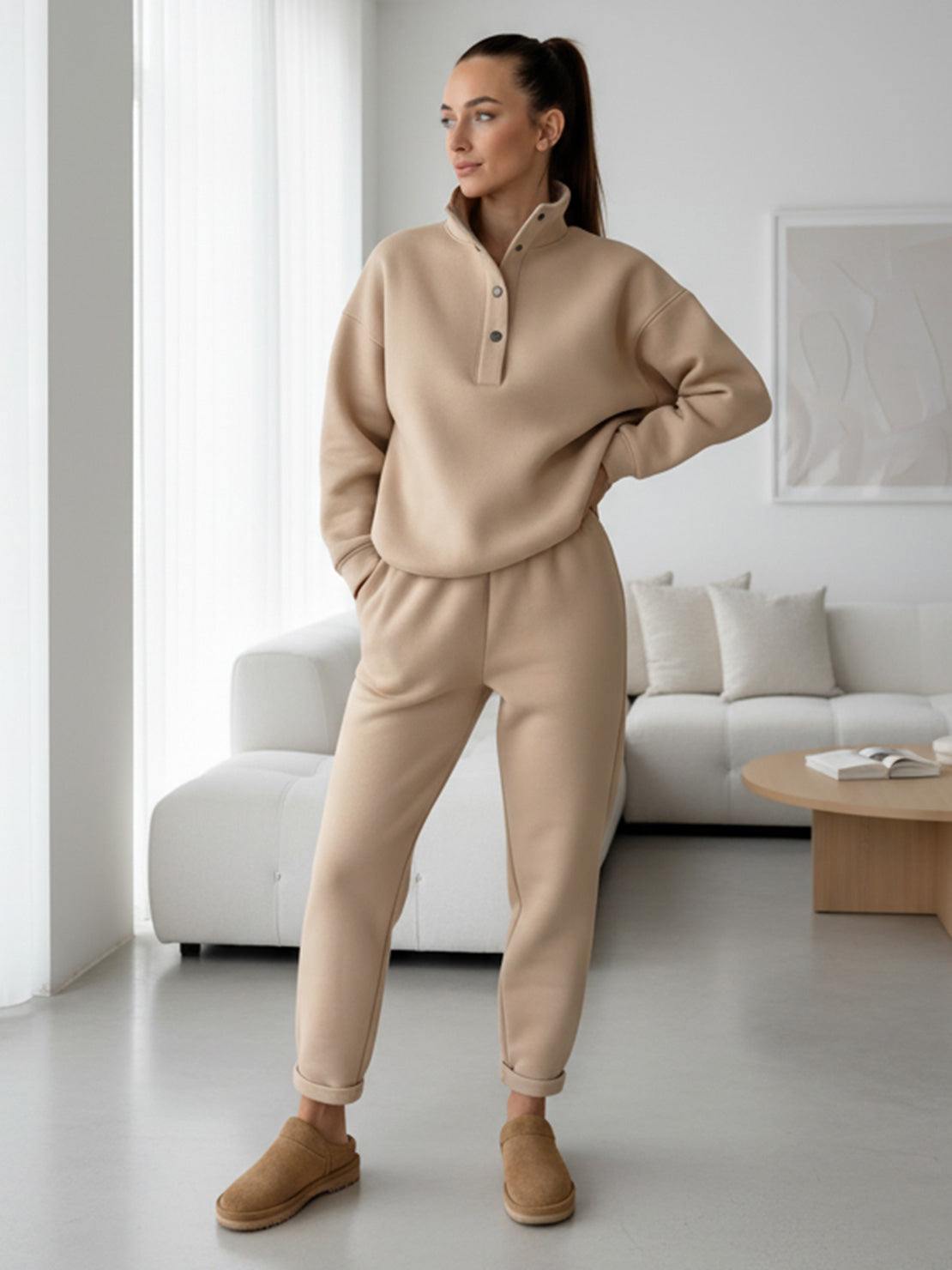Woman wearing beige warm and easy two-piece set with pullover hoodie and matching pants in modern living room