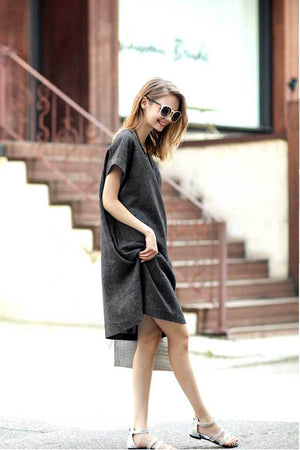 Woman wearing dark gray short sleeve shift dress with side pockets and sunglasses walking outdoors