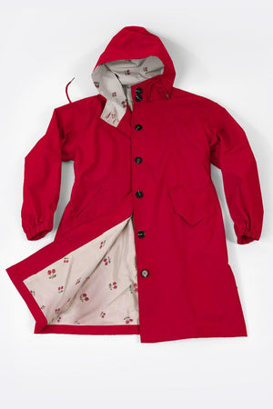 Red water resistant oversized windbreaker with hood and button closure, featuring light-colored inner lining with pattern.