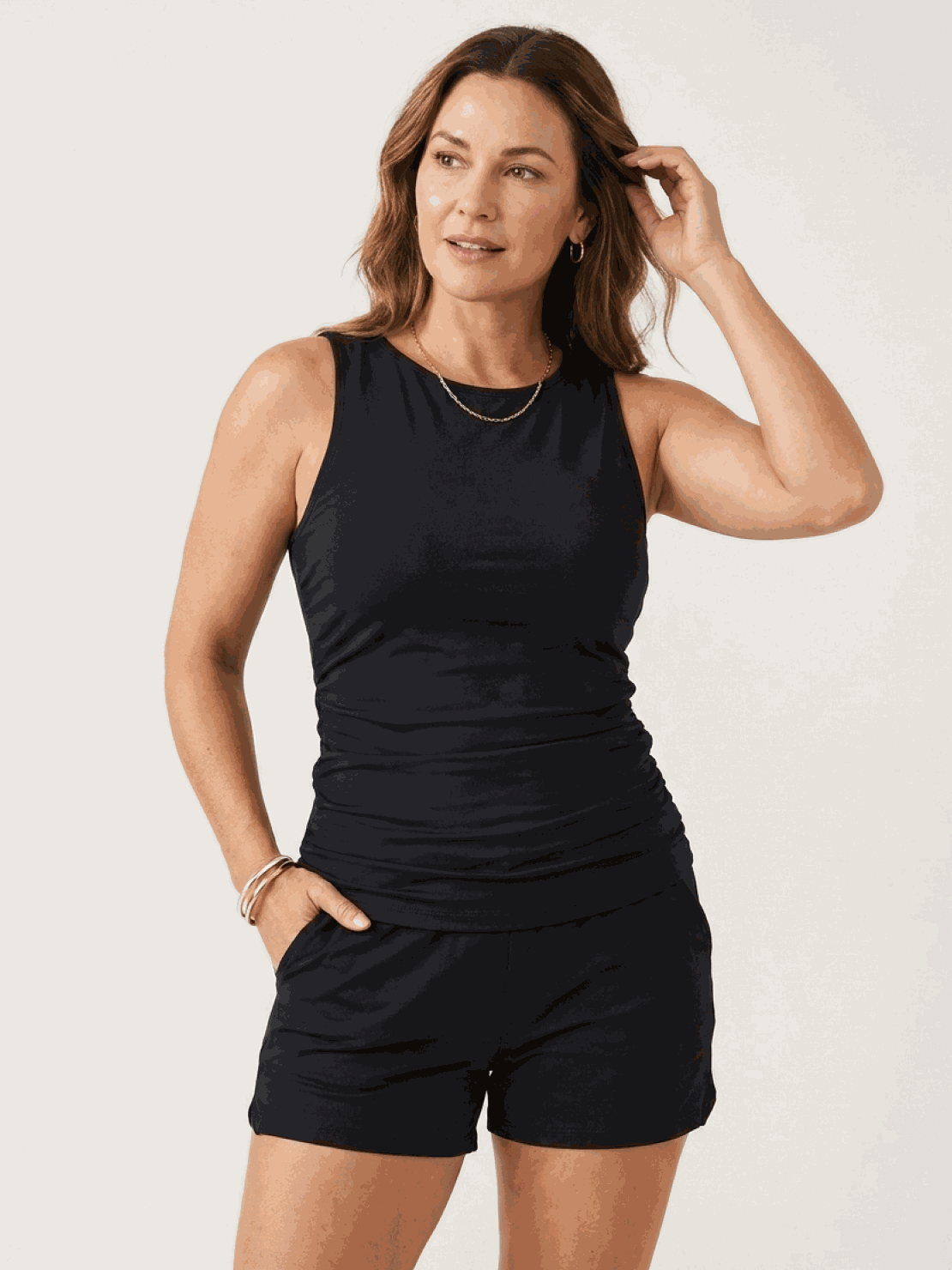 Woman wearing a high-neck ruched tankini set with gathered side seams and built-in brief at the beach