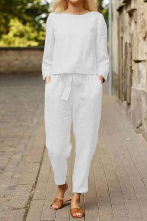 Woman wearing white cotton-linen monochrome relaxed longline top and wide-leg pants with brown sandals outdoors