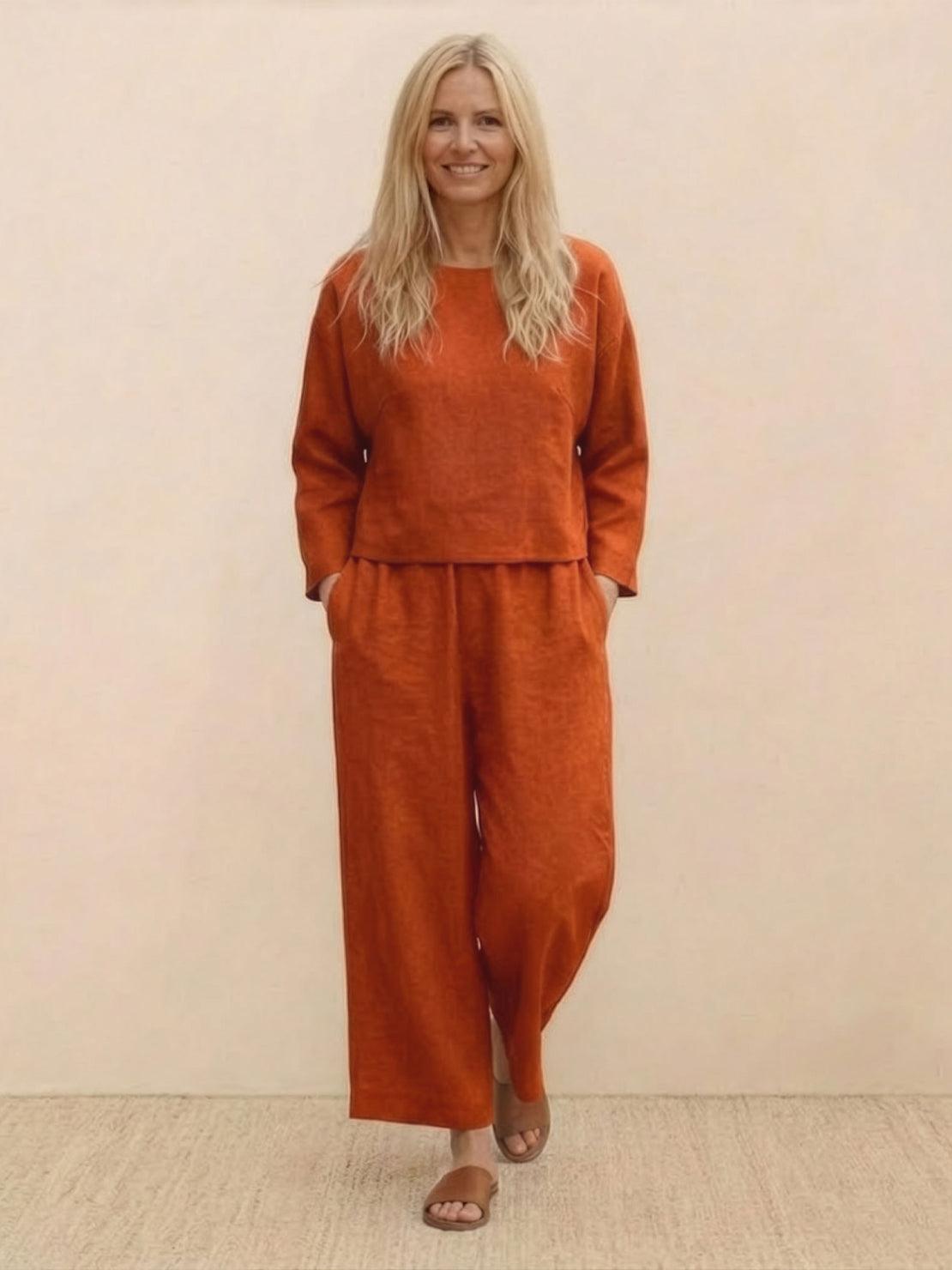 woman wearing loose solid color rust orange two-piece set with long sleeves and wide-leg pants