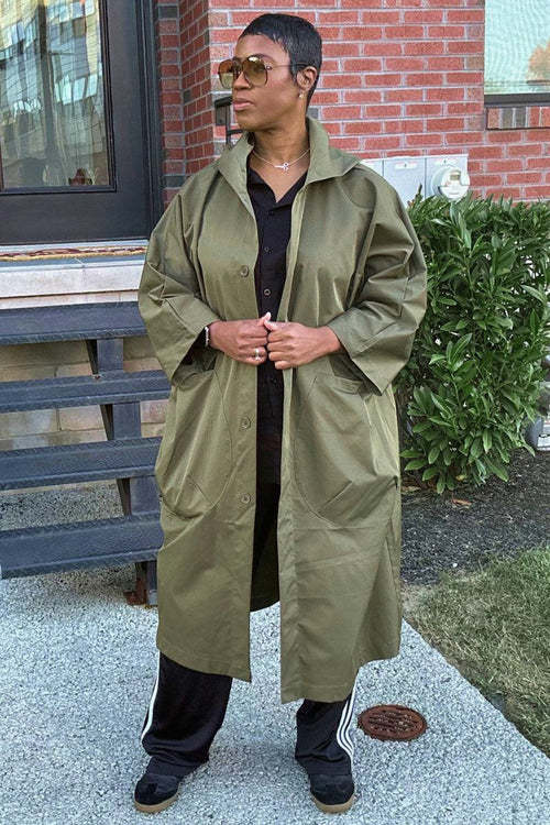 One size fits all oversized water resistant windbreaker jacket in olive green with longline body and snap-button closure worn outdoors