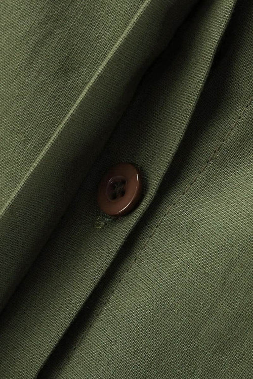 Close-up of oversized 100% cotton shirt fabric in olive green with brown button detail