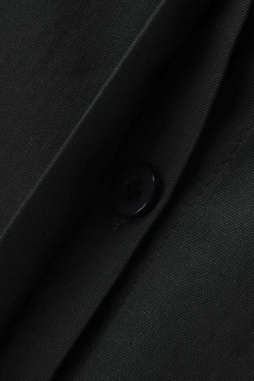 Close-up of oversized 100% cotton black shirt fabric with button detail