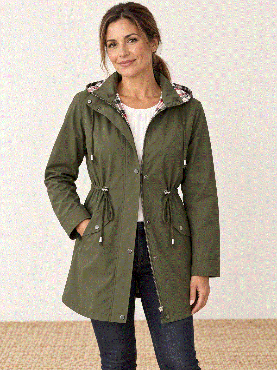 woman wearing plaid-lined hooded rain jacket with red and cream tartan lining and waterproof shell outdoors