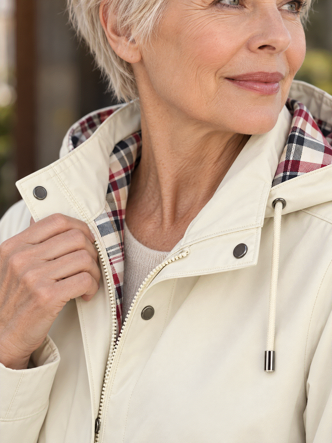 woman wearing plaid-lined hooded rain jacket with waterproof shell and tartan lining outdoors