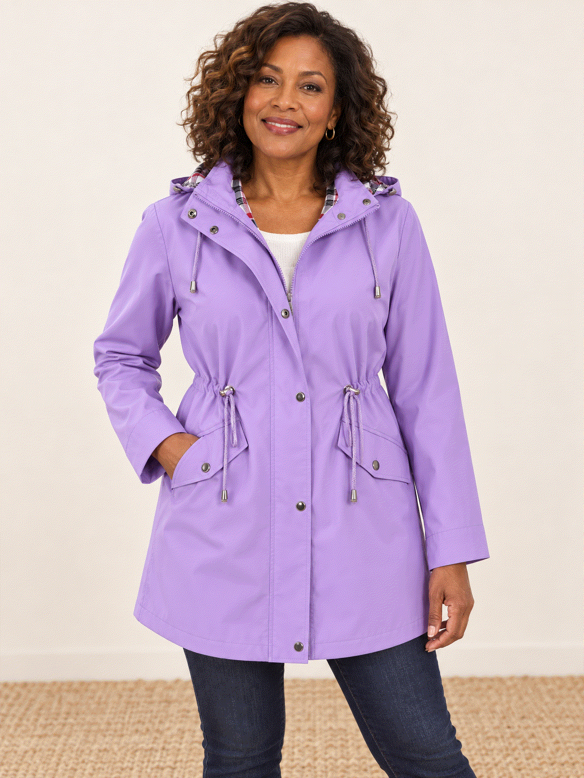 woman wearing a plaid-lined hooded rain jacket with snap flap pockets and drawstring waist