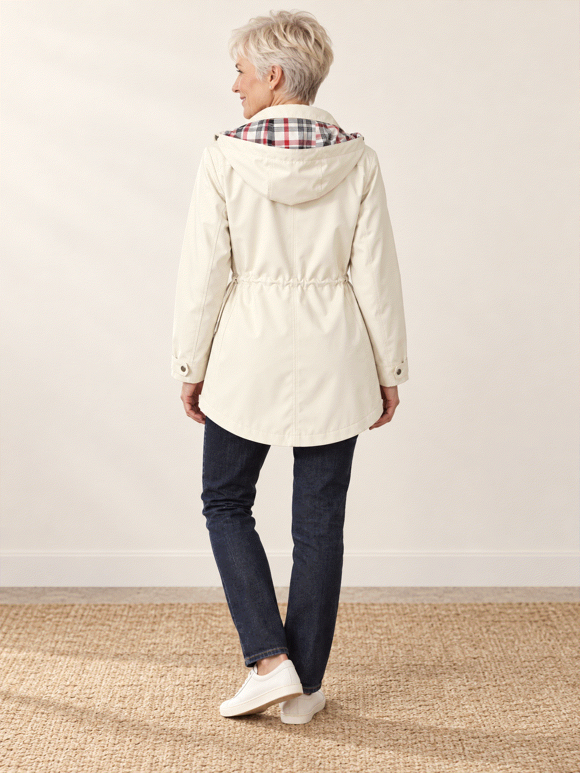 woman wearing plaid-lined hooded rain jacket with tartan lining and drawstring waist outdoors