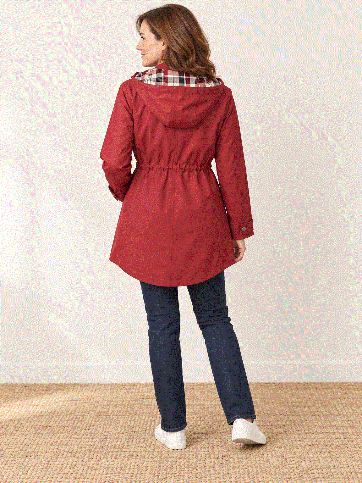 woman wearing plaid-lined hooded rain jacket with drawstring waist and snap pockets