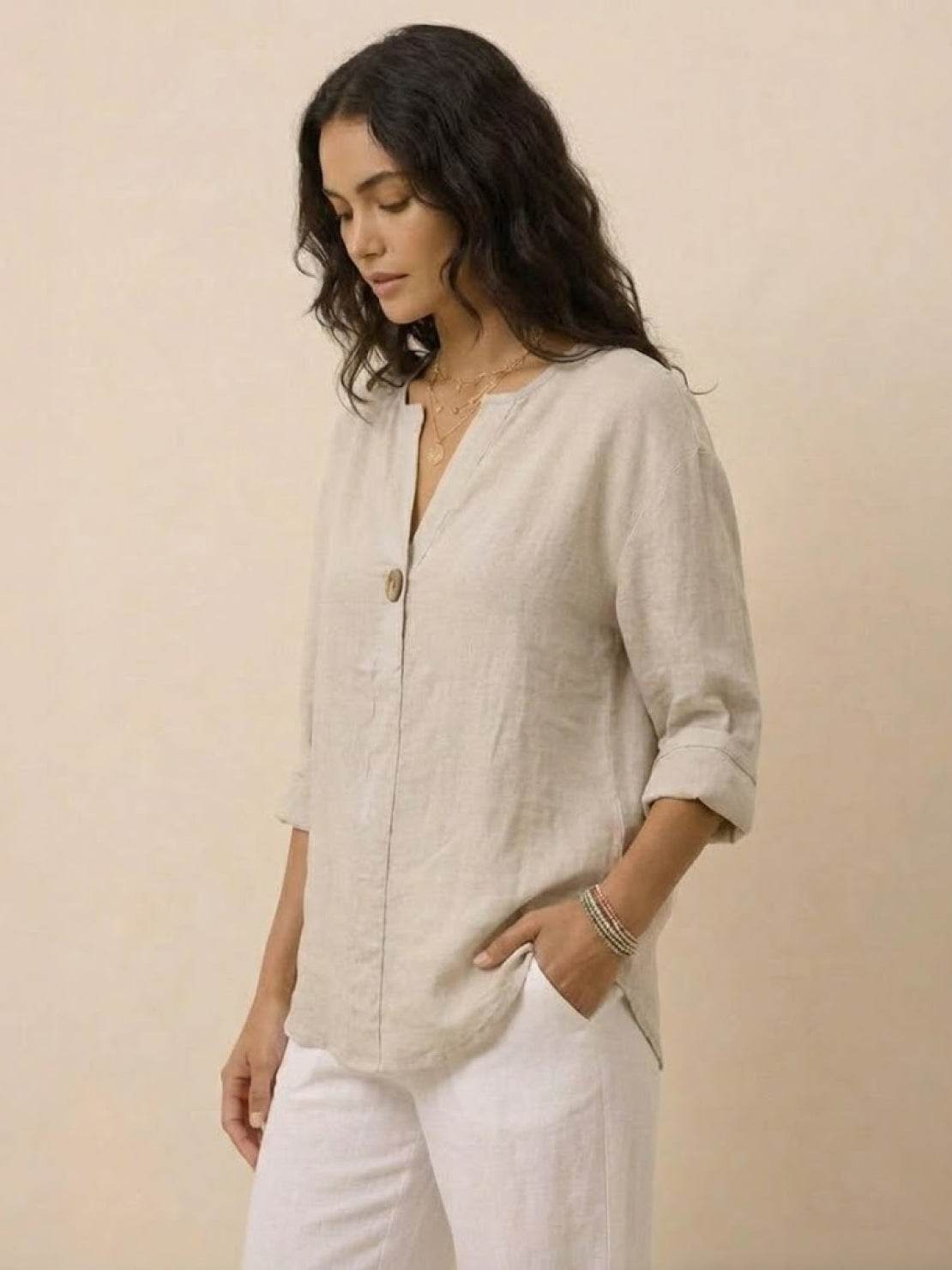 Woman wearing a beige pure linen age-defying shirt with button detail and rolled sleeves