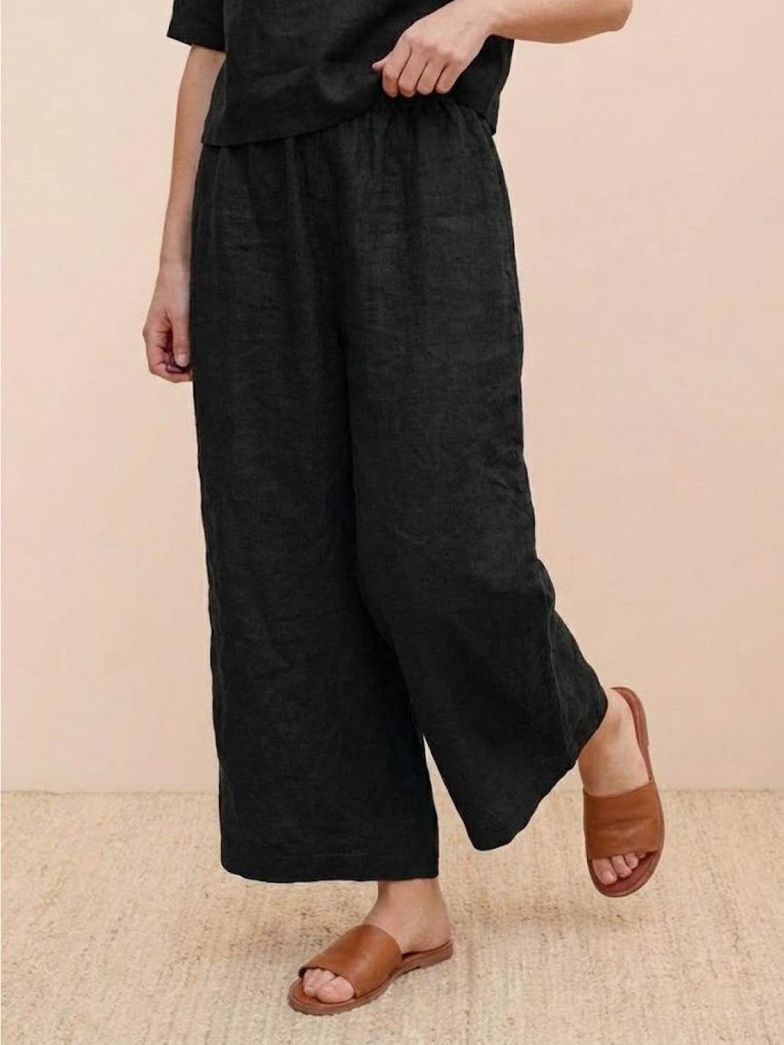 Woman wearing black wide-leg loose fit co-ord set pants paired with brown sandals.