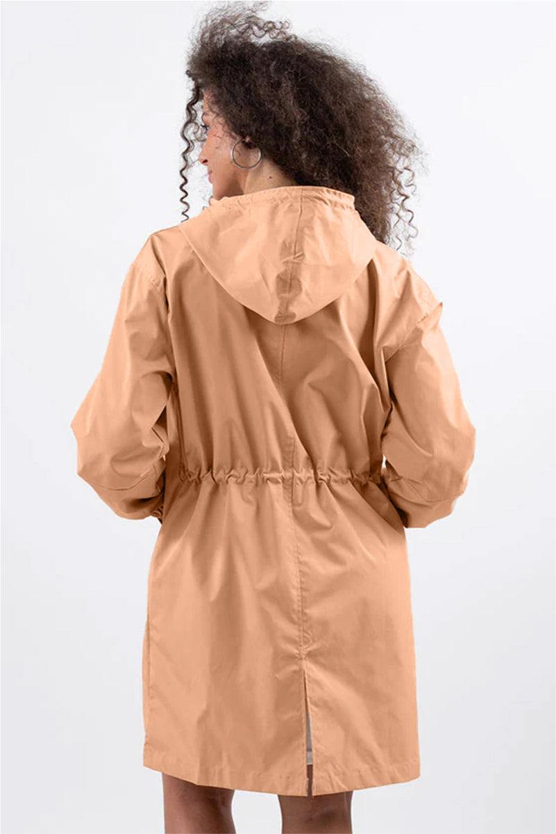 Back view of woman wearing oversized tan Rain Couture Windbreaker with adjustable hood and cinched waist