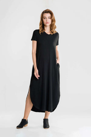 Woman wearing black side slit maxi dress with short sleeves and pockets standing against a white background
