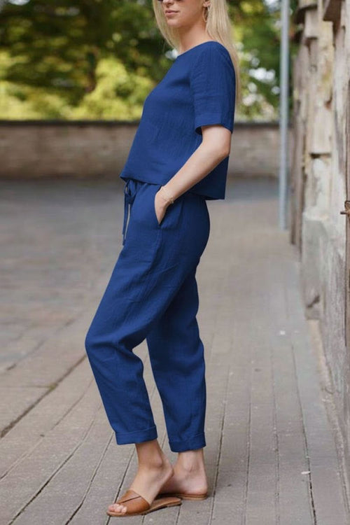 Woman wearing relaxed fit navy blue cotton linen set with short sleeve top and straight-leg pants outdoors