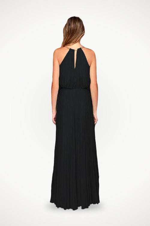 Back view of a woman wearing a black sleeveless belted maxi pleated dress with a keyhole neckline.
