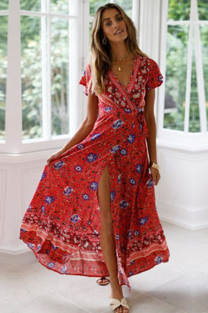 Woman wearing red Bohemian floral print wrap dress with V-neck and high slit in bright room