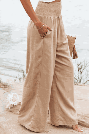 Beige high-waist cotton linen palazzo pants with wide legs and pockets on beach background