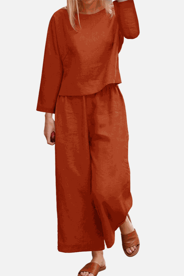 Woman wearing loose solid color two-piece set with long sleeve top and wide-leg pants in burnt orange color
