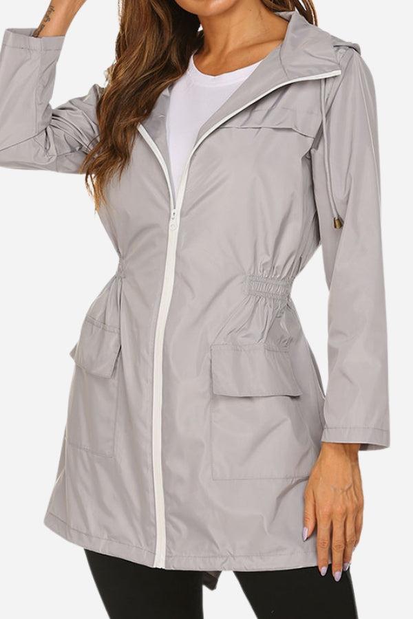 Woman wearing gray outdoor and travel hooded raincoat windbreaker jacket with zip front and pockets