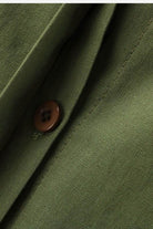 Close-up of olive green relaxed shirt and trousers fabric with brown button detail