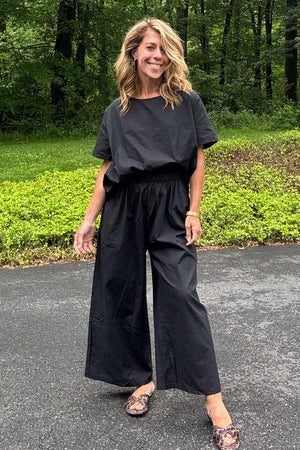 Woman wearing black loose fit co-ord set with wide-leg pants and relaxed short sleeve top outdoors
