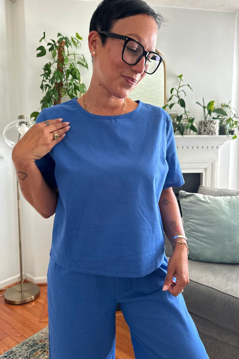 woman wearing blue loose fit co-ord set with relaxed short sleeve top and wide-leg bottoms in casual indoor setting
