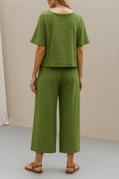 Back view of a woman wearing a green loose fit co-ord set with relaxed short sleeve top and wide-leg cropped pants paired with sandals.