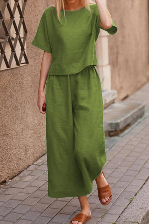 Woman wearing green loose fit co-ord set with wide-leg pants and short-sleeve top walking on sidewalk
