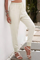 Woman wearing relaxed chic elastic ankles pants in light beige with drawstring waist and cuffed ankles
