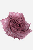 Soft lightweight linen scarf in mauve with frayed edges, folded in a rose shape