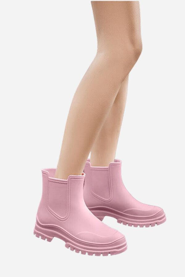 Pink non-slip rain boots with SuperGrip soles worn on model's legs