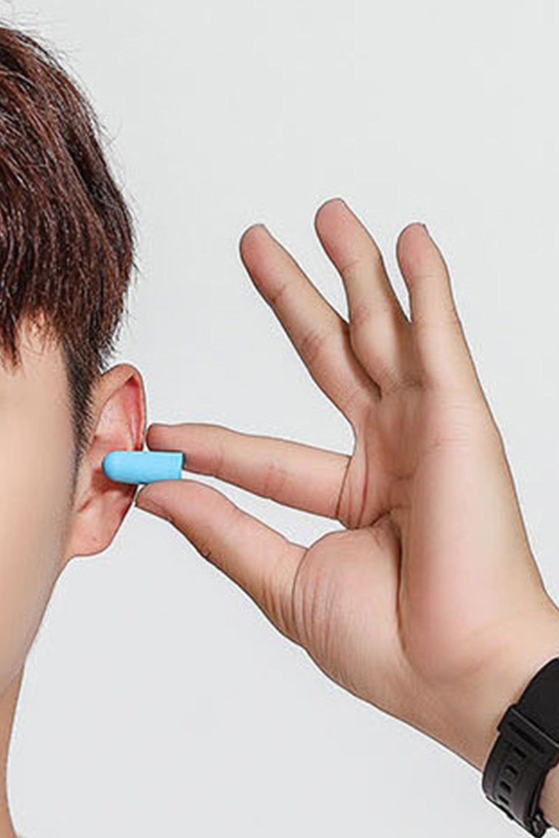 Person inserting blue foam earplug, part of Travel Comfy Kit for noise reduction during travel