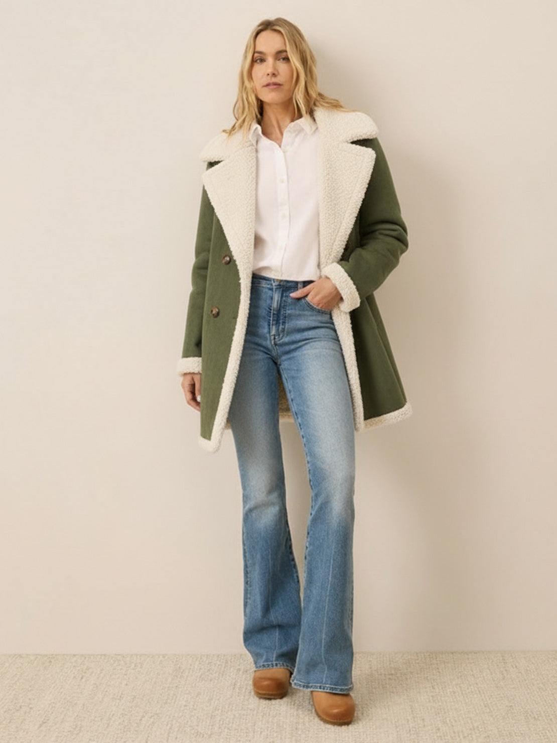 woman wearing faux suede sherpa coat with contrast sherpa collar and trim, mid-thigh length, double-breasted front, and side pockets