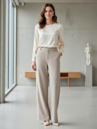 Woman wearing beige wide-leg thermal wool blend trousers with cream long-sleeve top in modern indoor setting