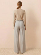 Woman wearing beige thermal wool blend trousers with wide-leg cut and elastic back waist standing against neutral background