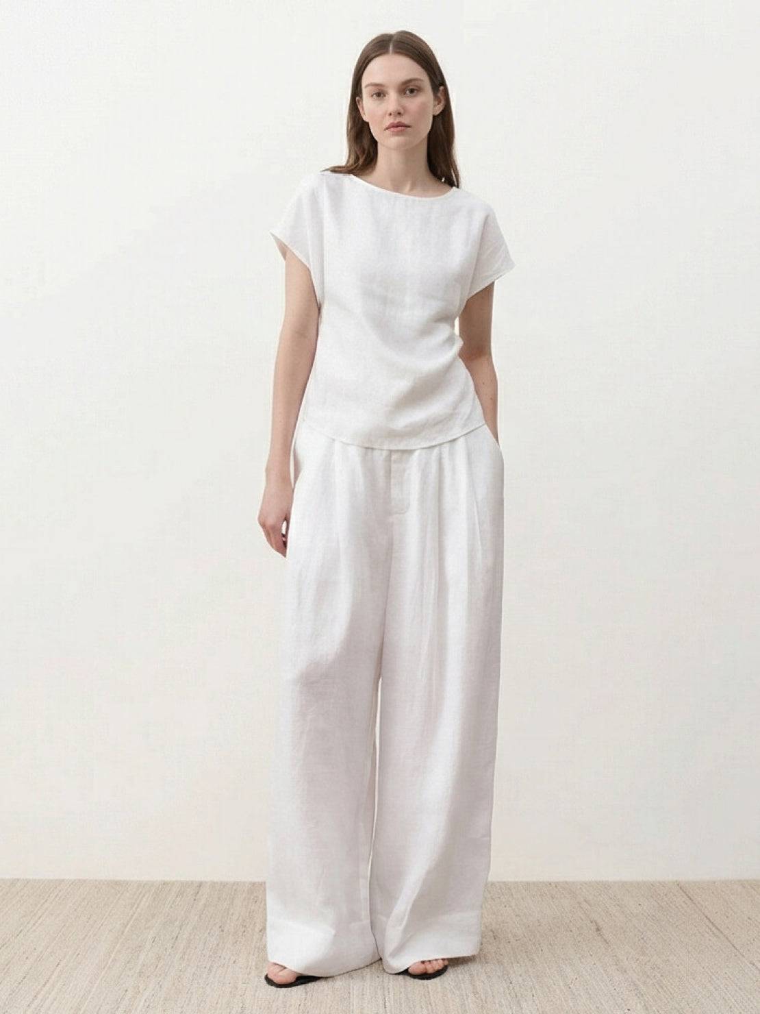 White Tencel-linen pleated wide-leg pants with structured waist and floor-skimming silhouette