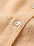 100% linen V-neck shirt with relaxed fit, long sleeves, wide button cuffs, and curved high-low hem
