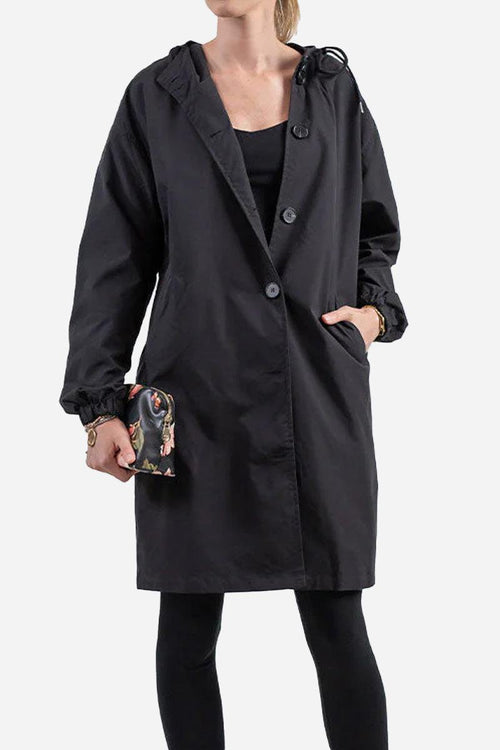Woman wearing black water resistant oversized hooded windbreaker jacket with buttons and elastic cuffs