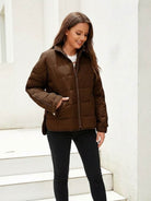 Woman wearing a brown lightweight puffer travel jacket with front zipper and side pockets, styled casually with black pants.