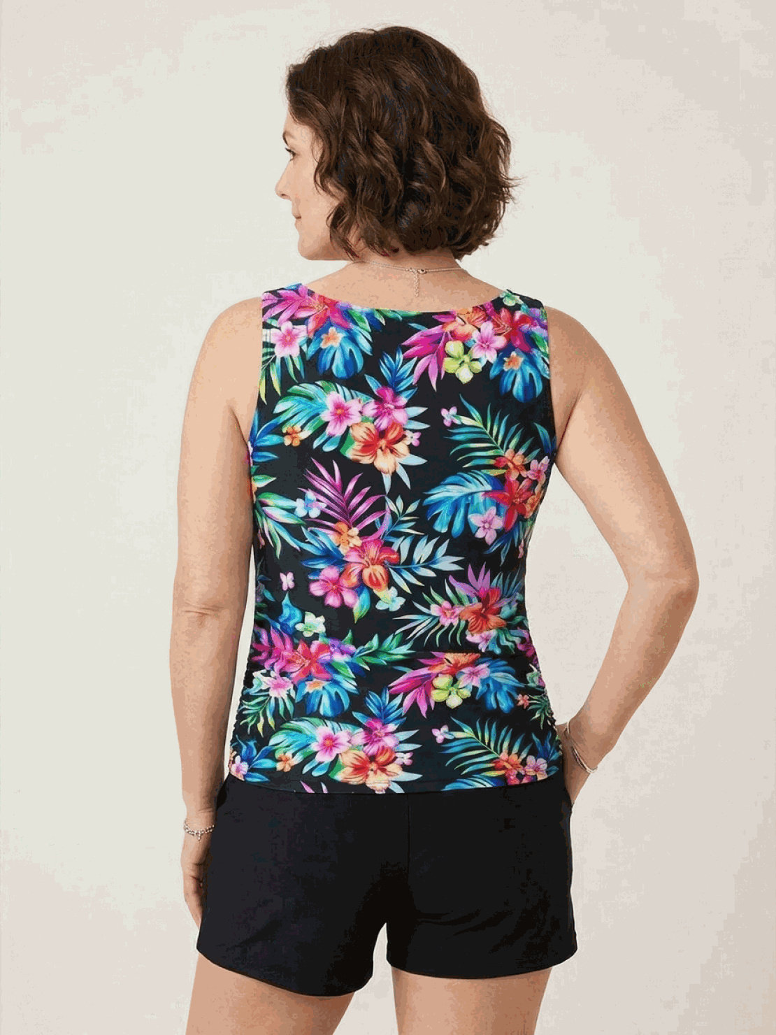 Woman wearing high-neck ruched tankini set with printed top and solid bottom at the beach