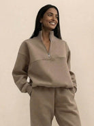 Woman wearing cotton-blended two-piece tracksuit with high collar and deep zipper in casual athleisure style