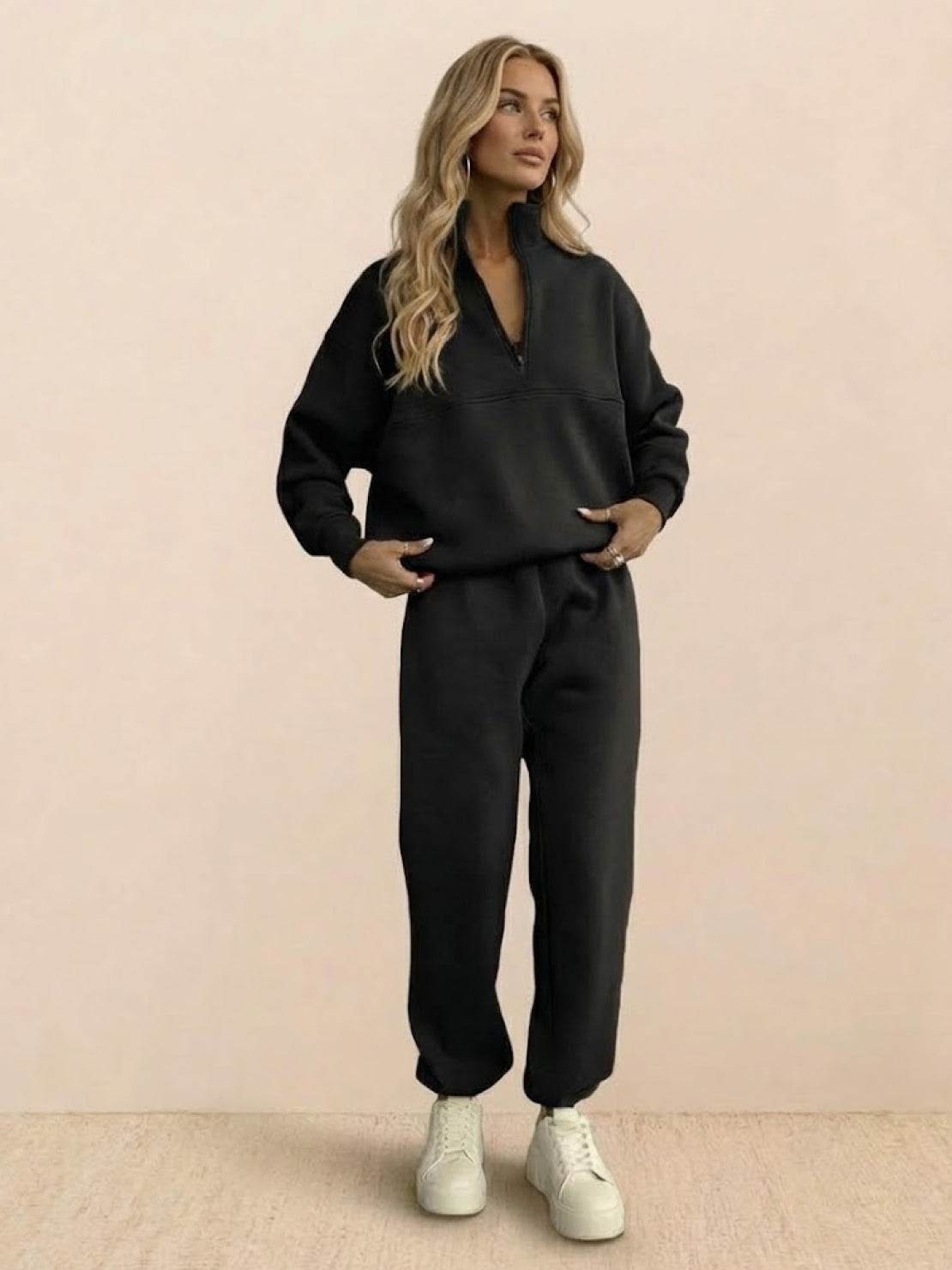 Woman wearing a cotton-blended two-piece tracksuit with high collar and zipper, styled for casual comfort and confident athleisure look