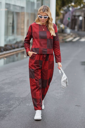 woman wearing red and black checkered cotton-linen monochrome two-piece set with long-sleeve top and wide-leg pants walking outdoors with white sunglasses and white handbag